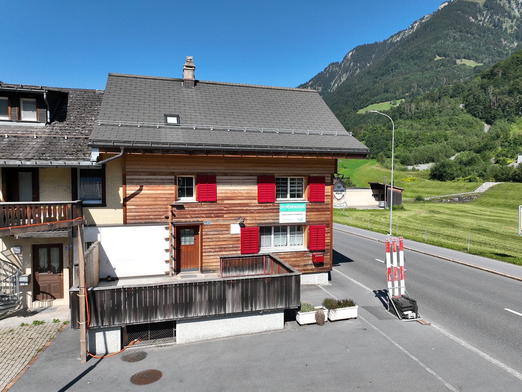 Südseite des Hirschen mit Terrasse, dahinter Wiesen und Berge
