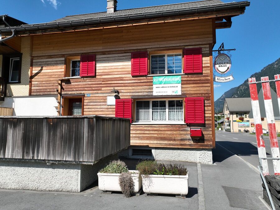Holzfassade mit roten Fensterläden und Wirtshausschild